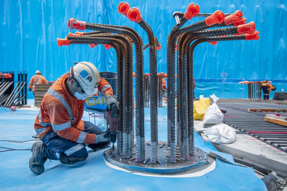 A worker drills bolts to secure the waterproofing to the top of one of the 99 piles installed in three rows down the entire 200-metre long station floor.